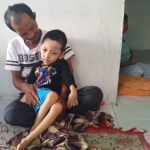 Aji Saputra, Bocah yang mengidap penyakit Hidrosefalus saat ayahnya berusaha memangkunya agar bisa duduk
